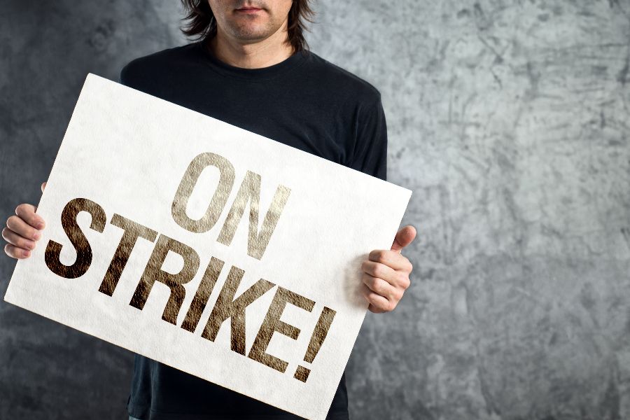 A man holding a placard marked &quot;ON STRIKE&quot;