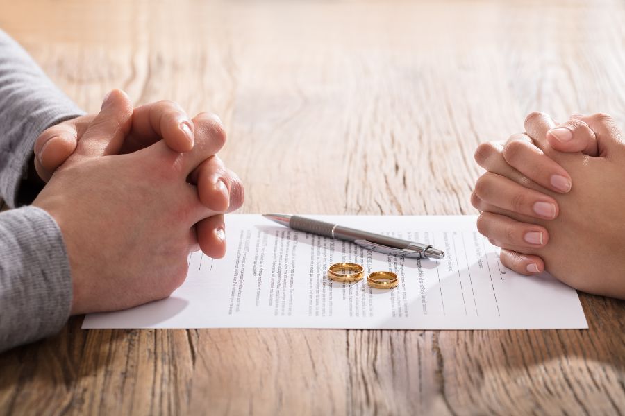 Two sets of clasped hands with wedding rings removed