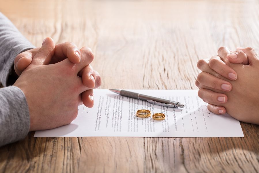 Two pairs of hands with two wedding rings between them