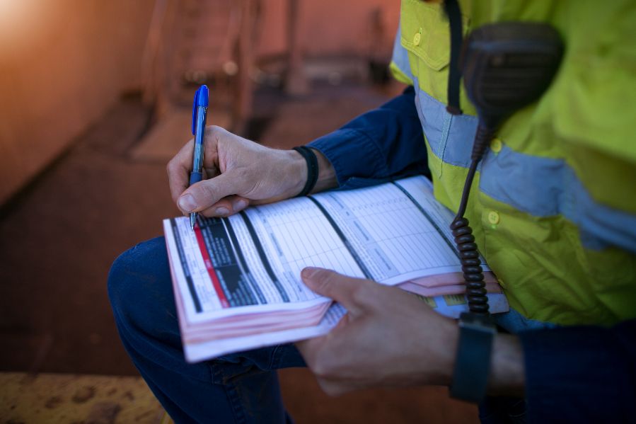 Close-up of a person wearing hi vis making notes on a form