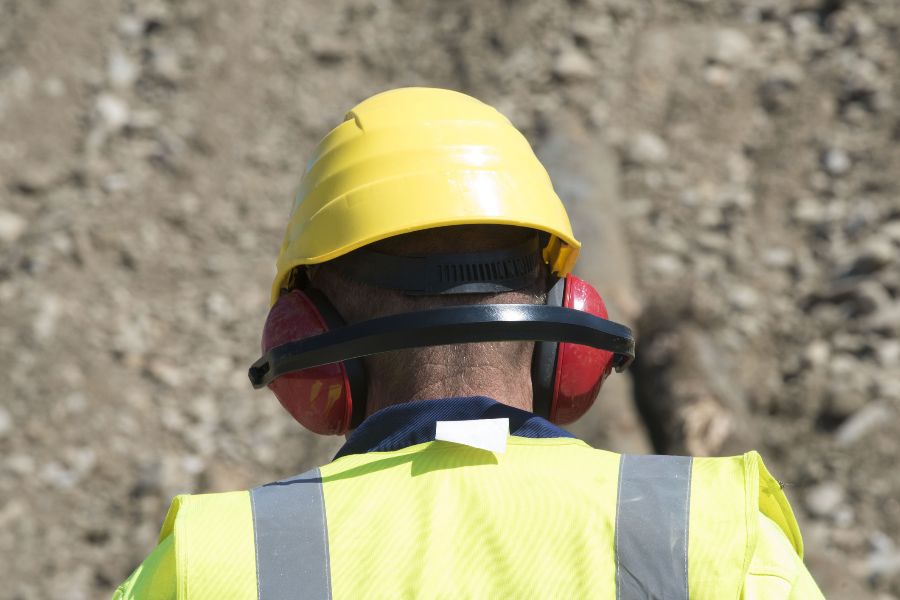 A view from behind of a worker wearing a hard hat and ear defenders