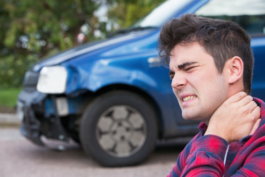 An injured man holding his neck after hitting something with his car