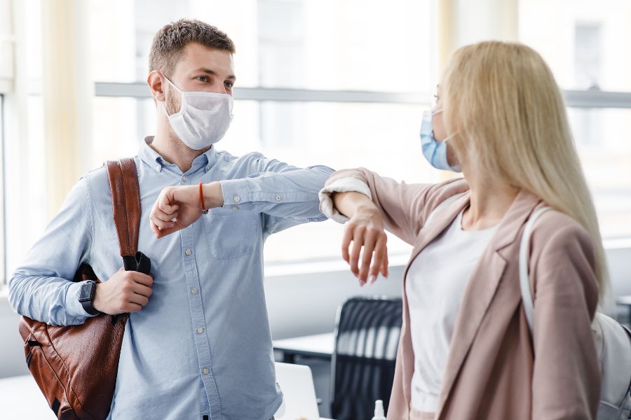 Two colleagues touch elbows in their workplace