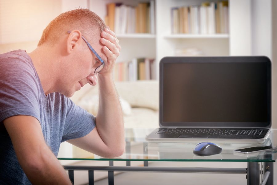 A stressed man in front of an open laptop