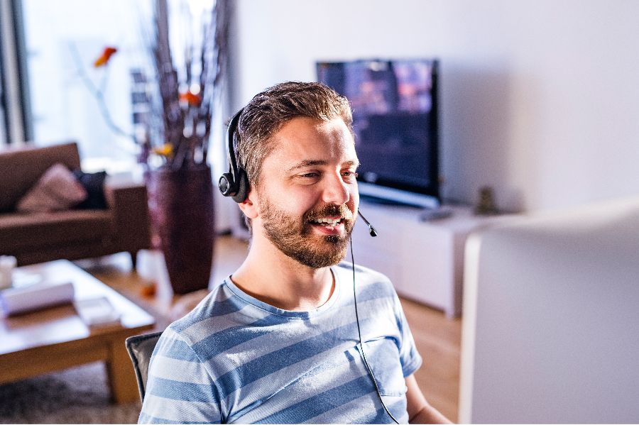 A man working from home, wearing a video conferencing headset