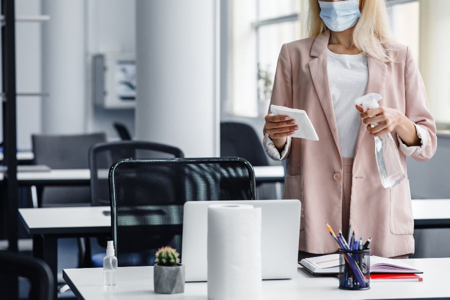 A woman cleans her workplace with sterilising fluid