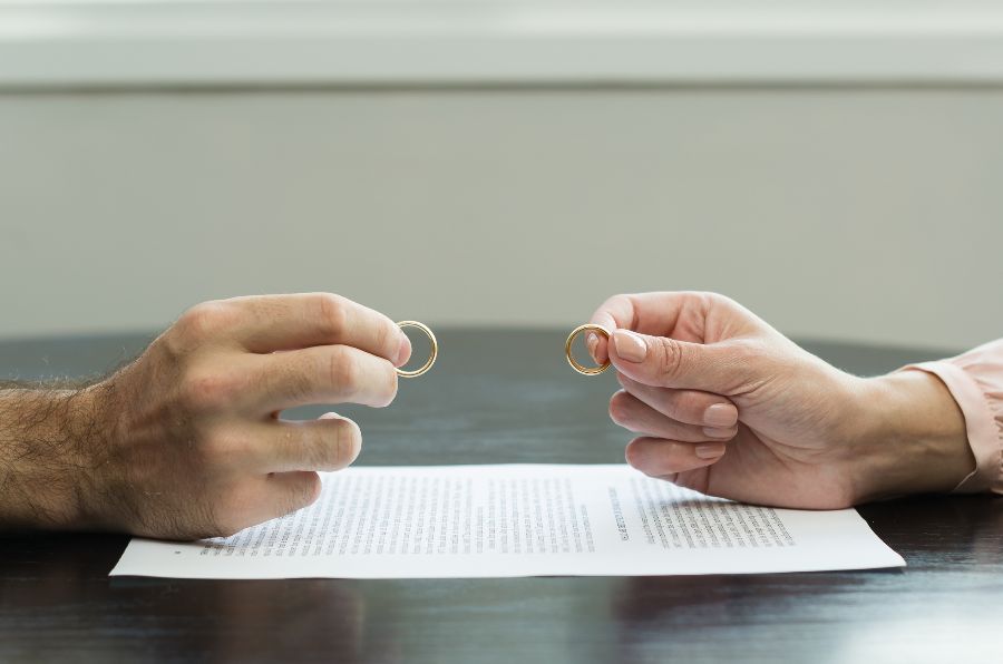 Hands of two people holding wedding rings across a table