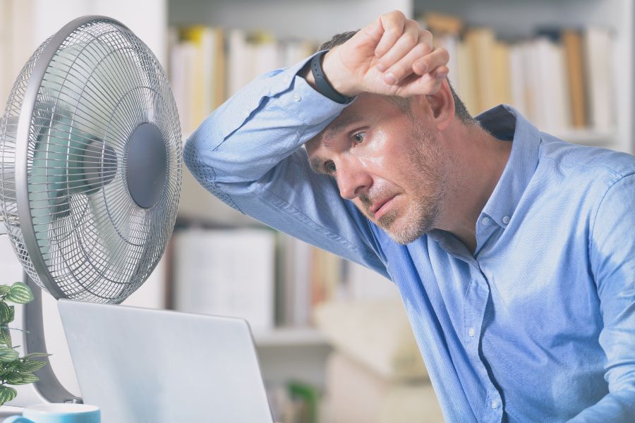 A very hot man sweating in front of a fan