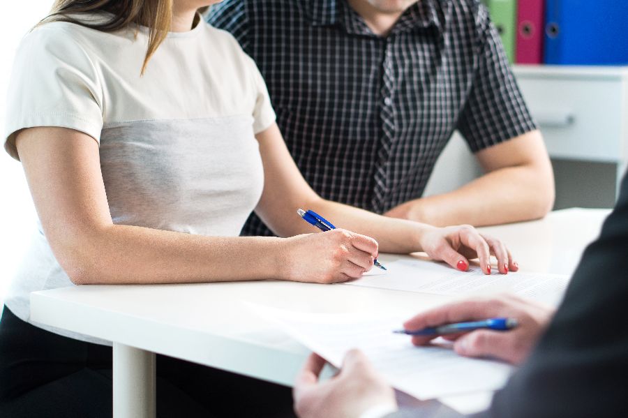 A couple sitting at a desk, signing a document