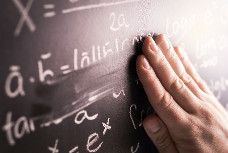 Fingers rubbing chalked mathematical formulae off a blackboard