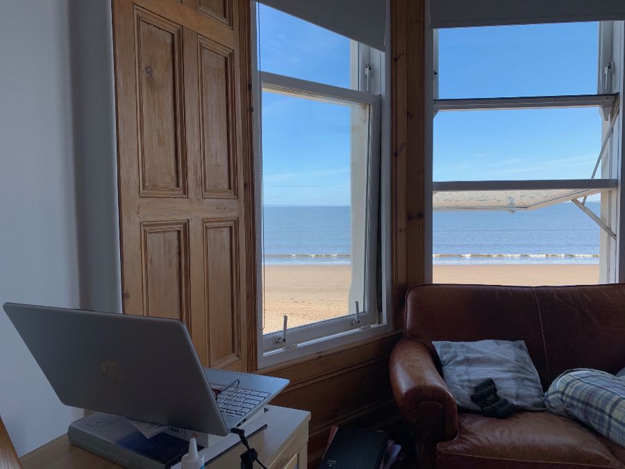 Laptop open by window with view onto the beach